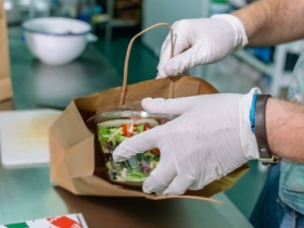 A healthy salad is packed into a paper bag in a kitchen